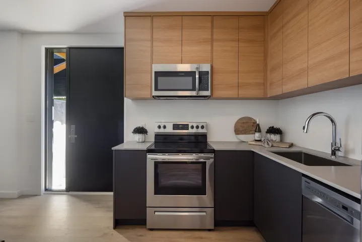 Kitchen with appliances with stainless steel finishes, modern cabinets, light wood-style flooring, and light stone counters