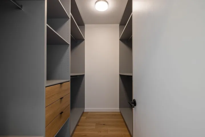 Walk in closet with light wood-type flooring