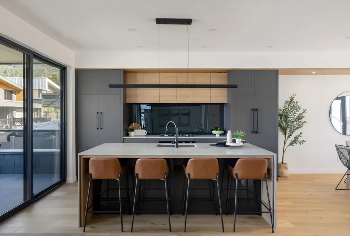 Kitchen featuring gray cabinetry, a kitchen breakfast bar, a center island with sink, modern cabinets, and light wood-style flooring