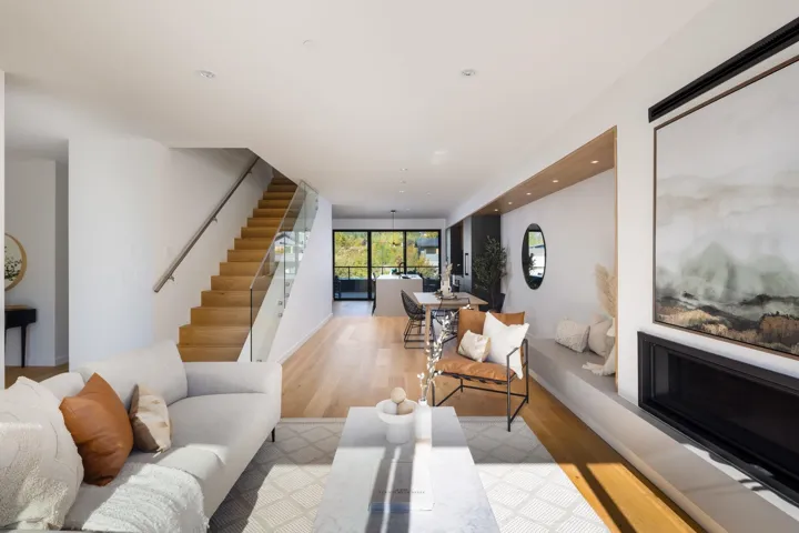 Living area with light wood-type flooring, recessed lighting, stairway, and a glass covered fireplace