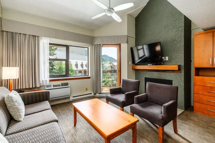 Living area featuring a ceiling fan, vaulted ceiling, a fireplace, and a baseboard heating unit