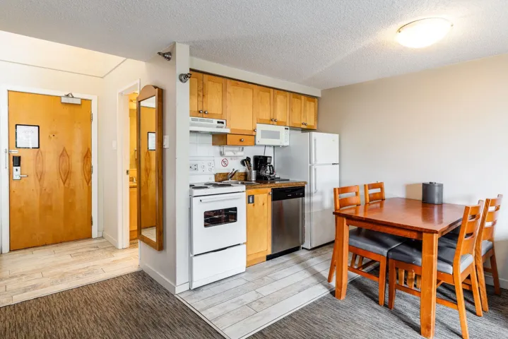 Kitchen featuring white appliances, a textured ceiling, light wood-style flooring, and under cabinet range hood