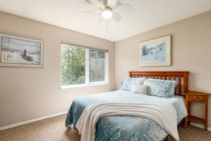 Bedroom featuring a white window with exterior greenery, neutral-toned walls, and textured carpeting