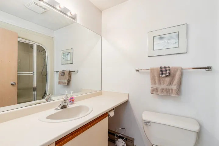 Bathroom featuring a spacious vanity with an integrated sink, large wall-mounted mirror, and a shower enclosure with sliding glass doors