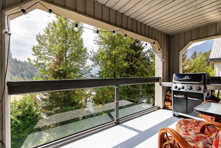Covered balcony featuring a wood-plank ceiling, string lighting, and a glass-paneled railing
