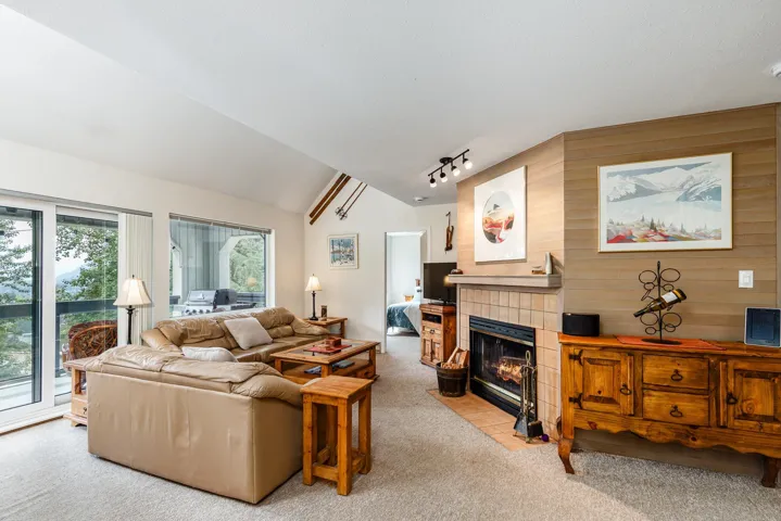 Living area featuring a vaulted ceiling and a fireplace with a tile surround and wood mantel