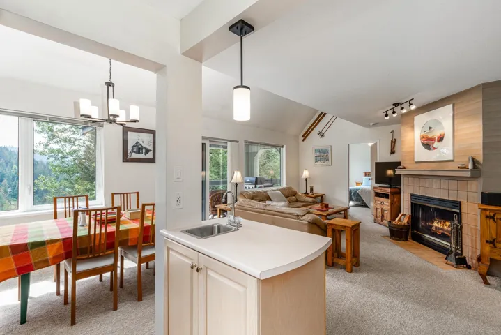 Open-concept living space featuring vaulted ceilings, a tiled fireplace with a mantel, and carpeted flooring