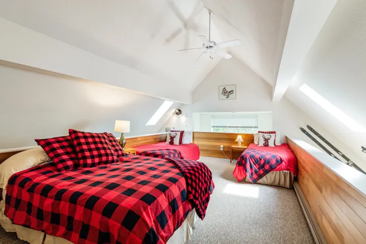 Loft space featuring a vaulted ceiling and exposed wood paneling