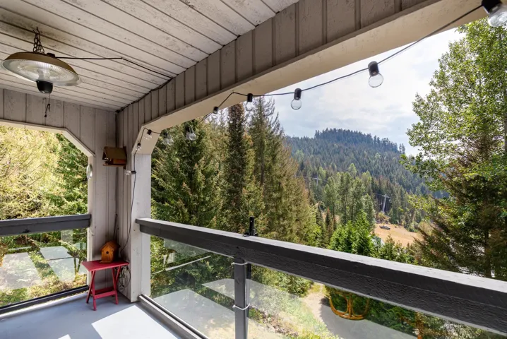 Covered balcony with a slatted wood ceiling and glass panel railing