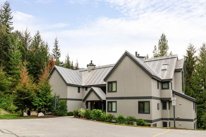 Multi-story residence featuring vertical siding in a neutral tone with dark trim accents