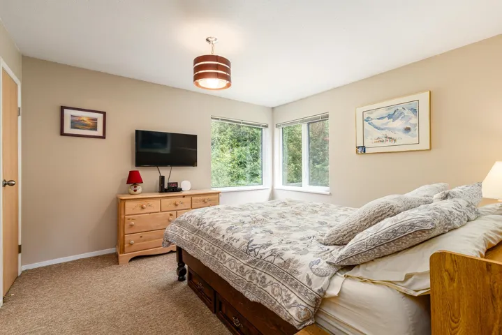 Windowed interior space with neutral wall tones and textured carpet flooring