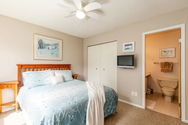 Bedroom featuring neutral wall paint, a built-in closet with bifold doors, and a ceiling fan with integrated lighting