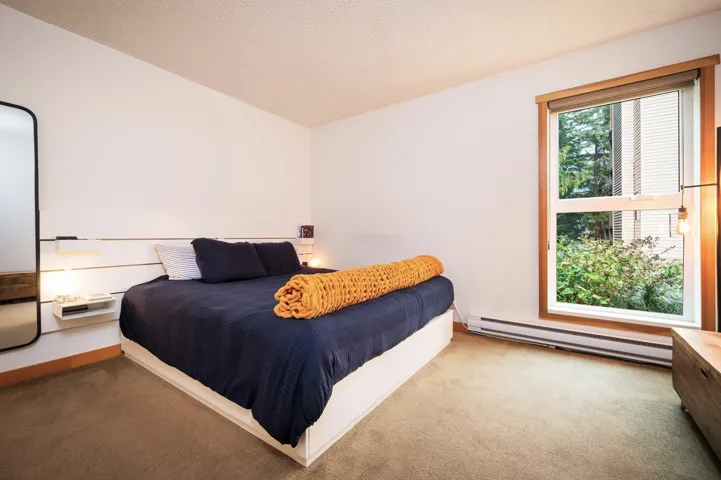 Bedroom with a baseboard heating unit, carpet floors, and a textured ceiling
