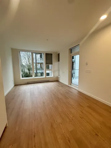 Unfurnished living room featuring plenty of natural light, light wood-style floors, and a baseboard radiator