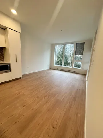 Unfurnished living room with light wood-style flooring, a baseboard heating unit, and recessed lighting