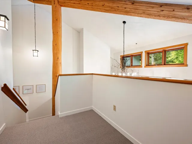 Hall with carpet flooring, a chandelier, and an upstairs landing