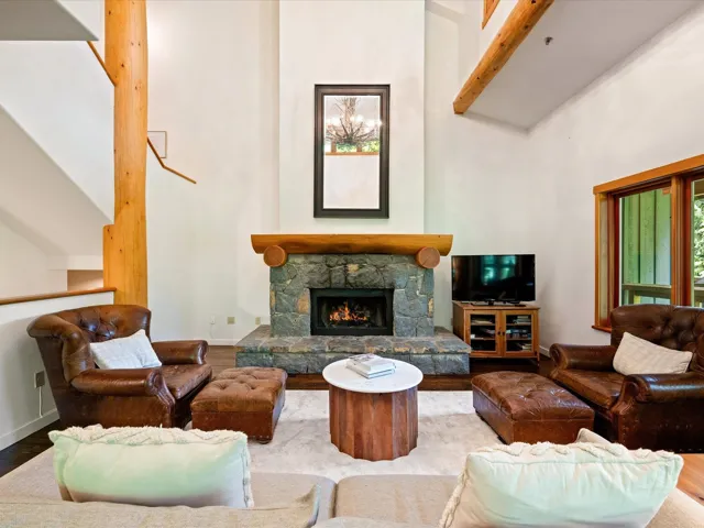 Living area with wood finished floors, a towering ceiling, and a fireplace