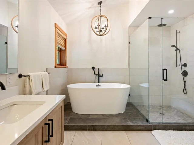 Bathroom featuring a stall shower, vanity, a freestanding bath, tile walls, and a chandelier