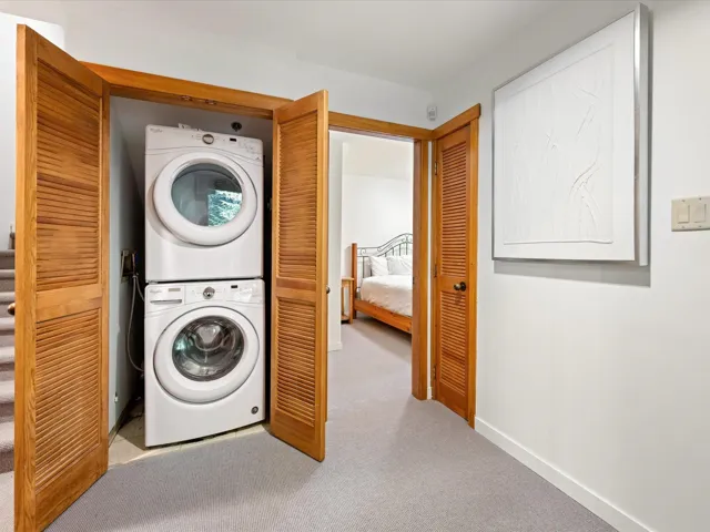 Laundry area featuring stacked washer / drying machine and carpet