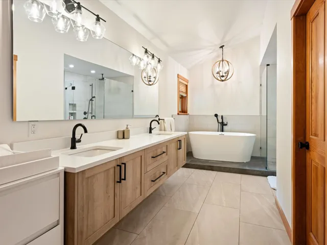 Full bath with a shower stall, a chandelier, double vanity, a soaking tub, and tile walls