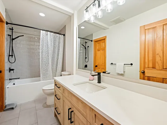 Bathroom featuring vanity, shower / bath combo with shower curtain, tile patterned floors, and recessed lighting