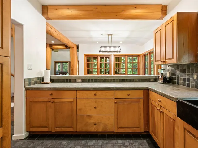 Kitchen with tasteful backsplash, healthy amount of natural light, brown cabinets, recessed lighting, and vaulted ceiling