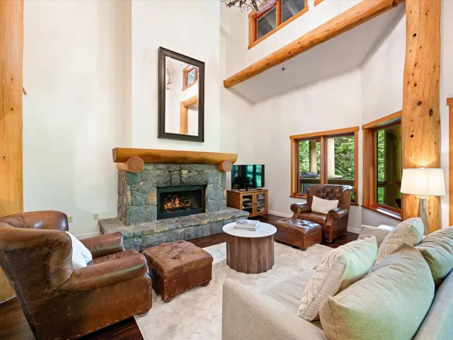 Living room with a high ceiling, a stone fireplace, and wood finished floors