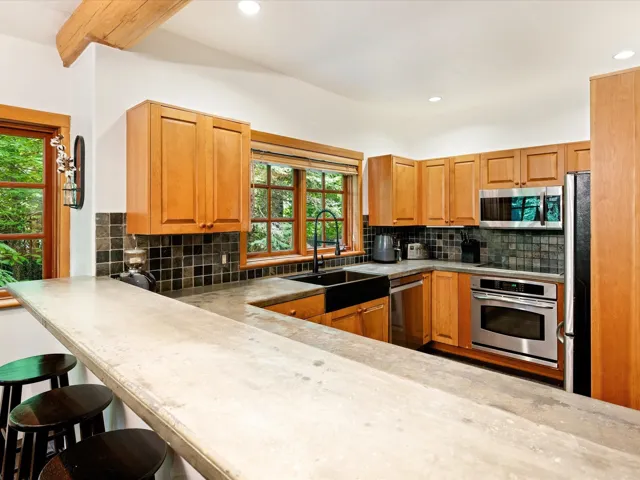 Kitchen featuring stainless steel appliances, healthy amount of natural light, decorative backsplash, recessed lighting, and a breakfast bar