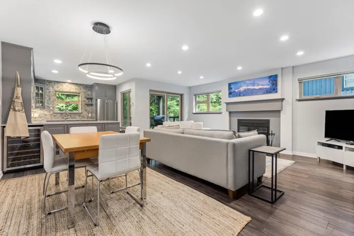 Living room featuring beverage cooler, recessed lighting, dark wood-style floors, a glass covered fireplace, and baseboards