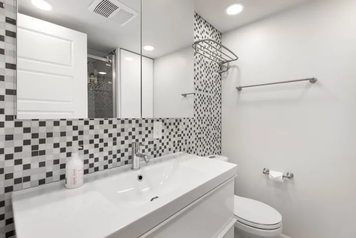 Full bath featuring decorative backsplash, toilet, recessed lighting, tiled shower, and vanity