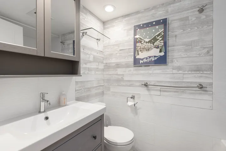 Bathroom featuring toilet, tile walls, vanity, and decorative backsplash
