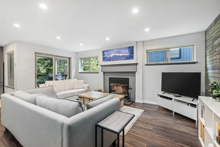 Living room featuring a glass covered fireplace, recessed lighting, dark wood-style floors, and baseboards