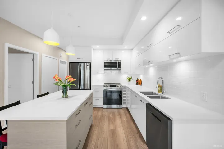 Kitchen with a breakfast bar area, white cabinetry, stainless steel appliances, hanging light fixtures, and recessed lighting