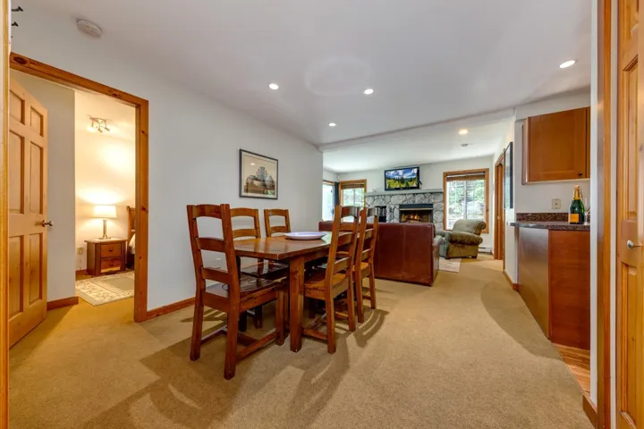 Dining room featuring light carpet, a fireplace, a bar, recessed lighting, and baseboards