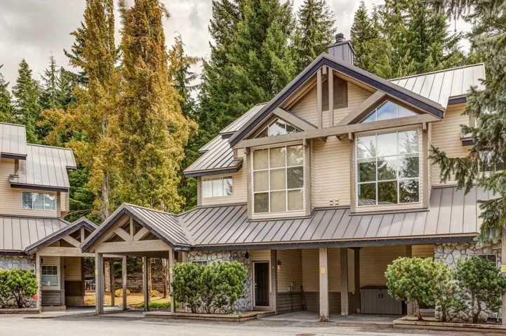 View of front of home featuring a standing seam roof, metal roof, a chimney, and stone siding
