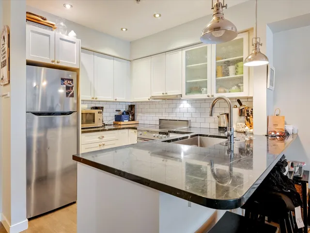 Kitchen featuring electric range oven, white microwave, freestanding refrigerator, a peninsula, and a sink