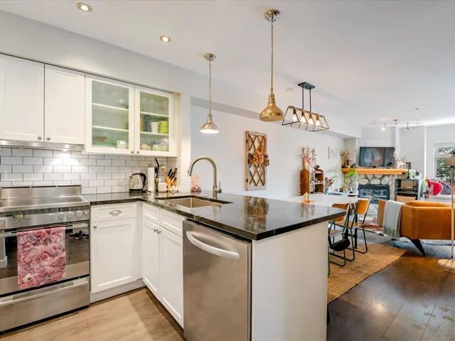 Kitchen featuring light wood-style flooring, a sink, open floor plan, appliances with stainless steel finishes, and backsplash