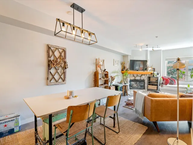 Dining space featuring rail lighting, a fireplace, baseboards, and wood finished floors