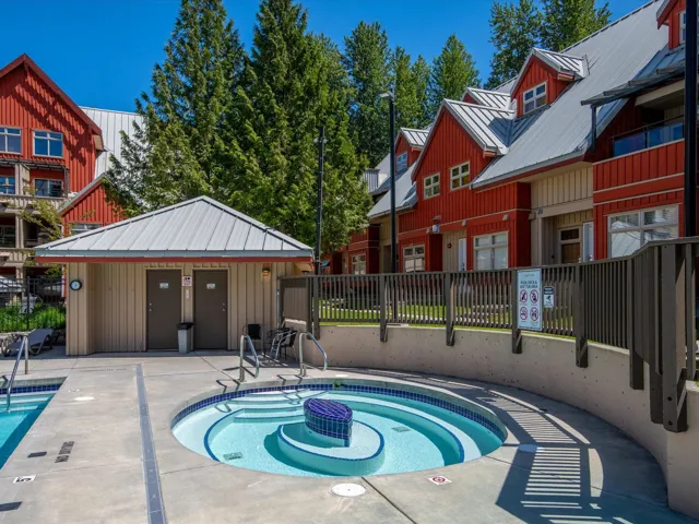 Community pool with a patio area, fence, and a hot tub
