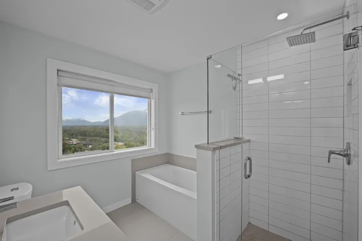 Bathroom featuring a mountain view, a bath, a shower stall, light tile patterned flooring, and vanity