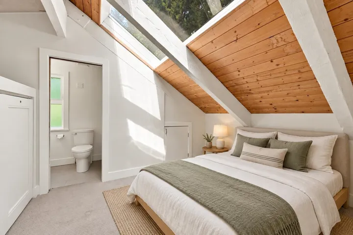 Vaulted ceiling featuring wood paneling and exposed white beams, integrated skylights, light-colored carpeting, and a built-in storage cabinet