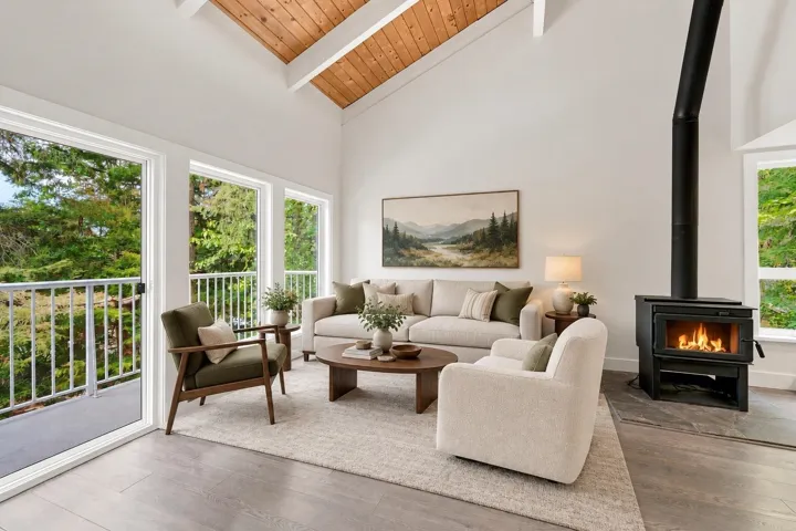 Vaulted wood-paneled ceiling, multiple large windows, a built-in wood-burning stove with a black stovepipe, and wood-finish flooring