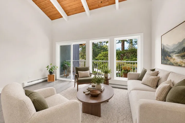 Vaulted wood-paneled ceiling with exposed beams, wood-finish flooring, and a sliding glass door to a balcony