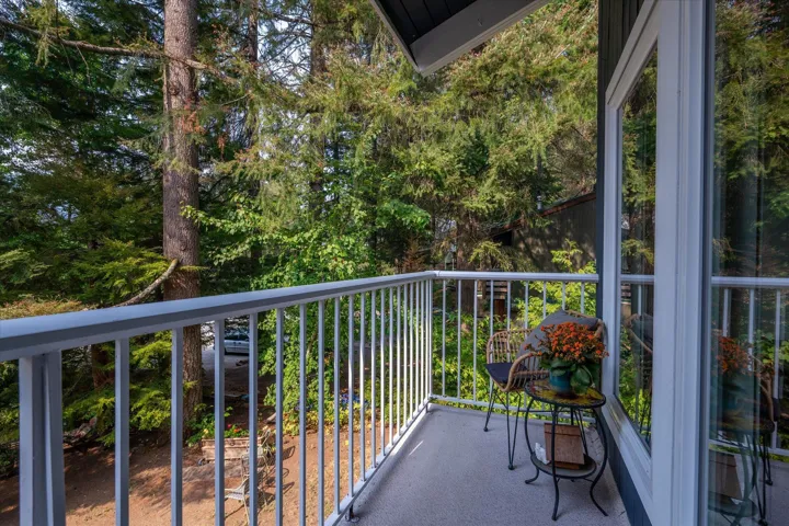Balcony featuring a light-colored railing, dark exterior siding, and a large glass door
