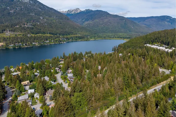 Lakeside community with surrounding natural landscape, mature trees, and mountain backdrop