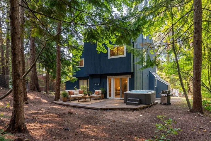 Expansive wooden deck with an integrated hot tub and glass sliding doors leading to the interior