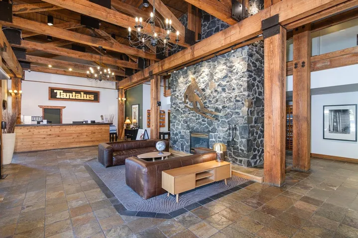 Living room featuring a stone fireplace, stone tile floors, and suspended lighting