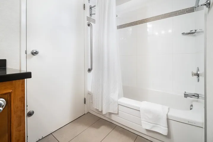 Full bathroom with vanity, light tile patterned floors, and shower / tub combo with curtain