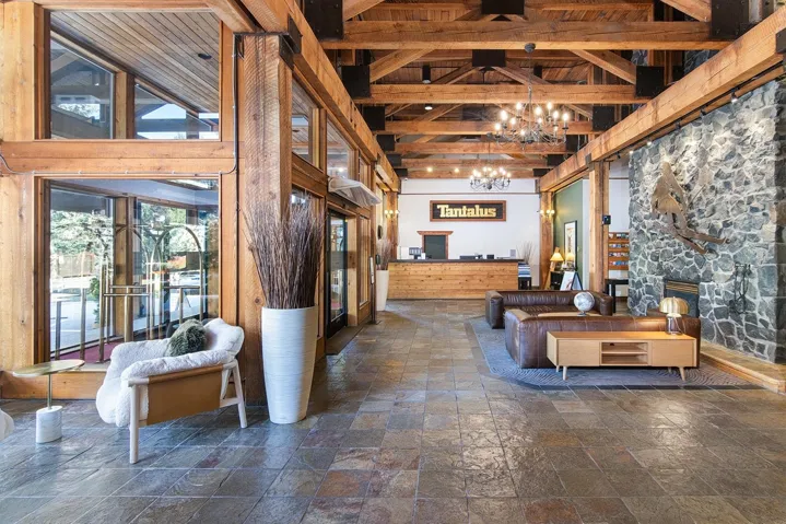 Living area with a stone fireplace, stone tile floors, suspended lighting, and lofted ceiling