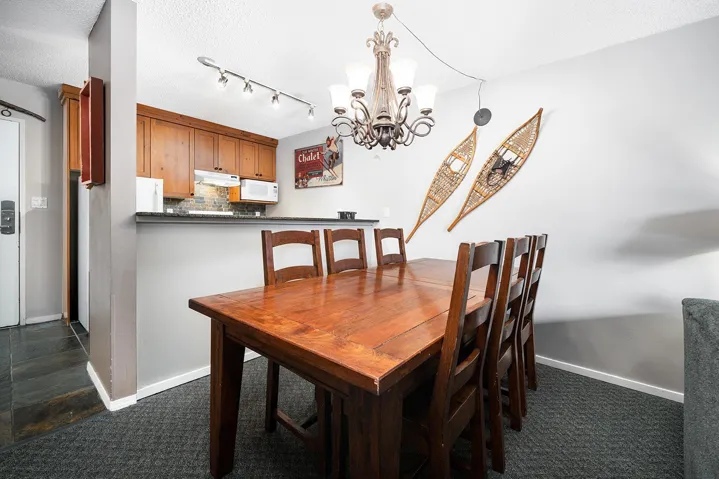 Dining area with suspended lighting, a textured ceiling, and dark colored carpet